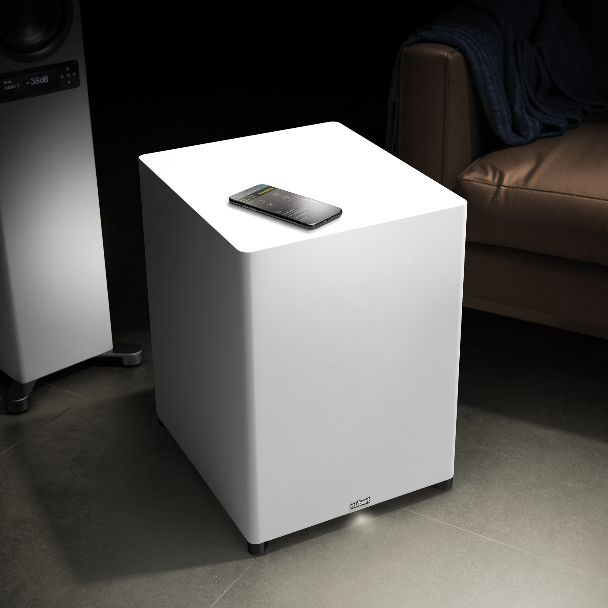 Weißer Subwoofer, Smartphone obenauf, in modernem Wohnzimmer.