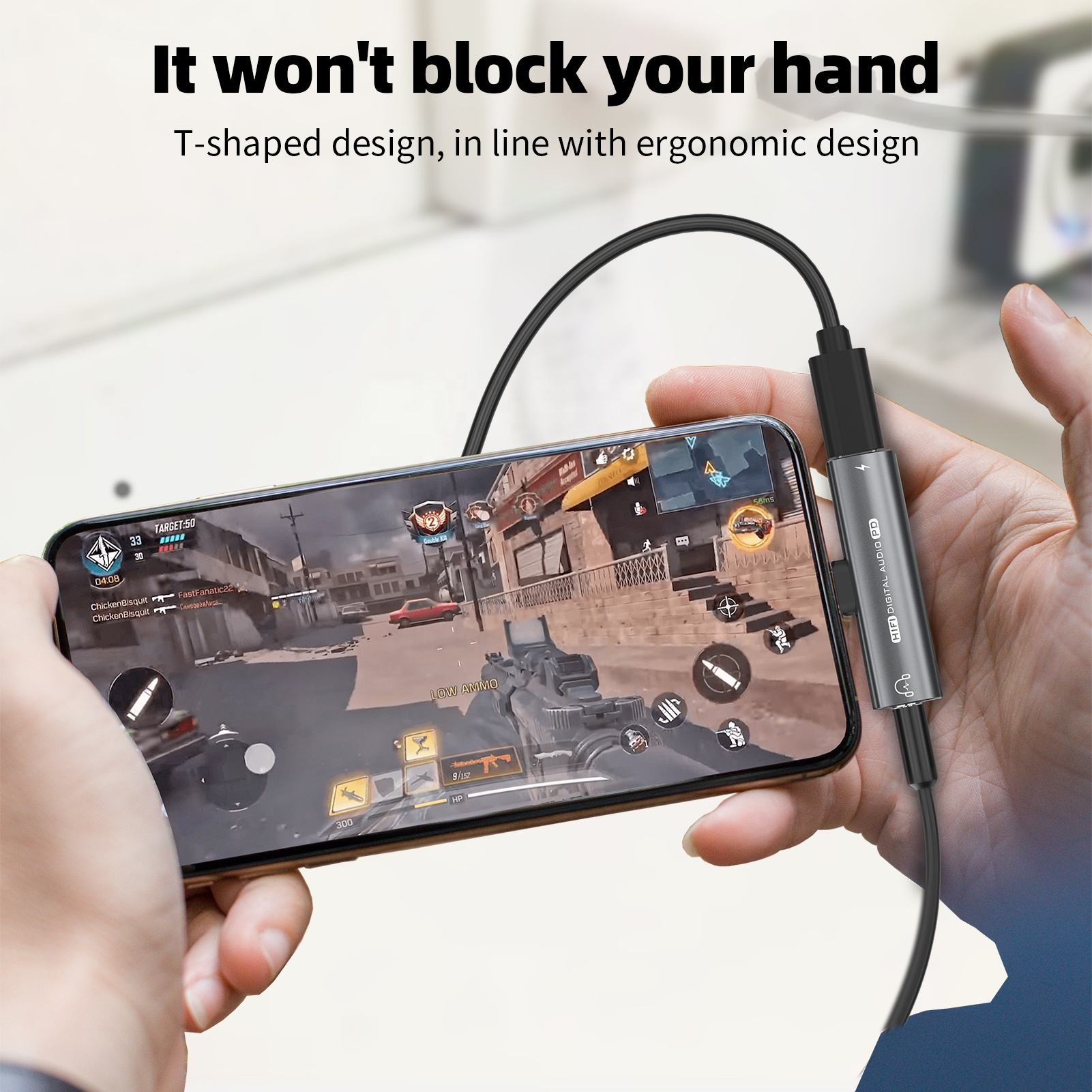 Osoba trzymająca telefon z podłączonym kablem, pokazująca scenę z gry wideo.