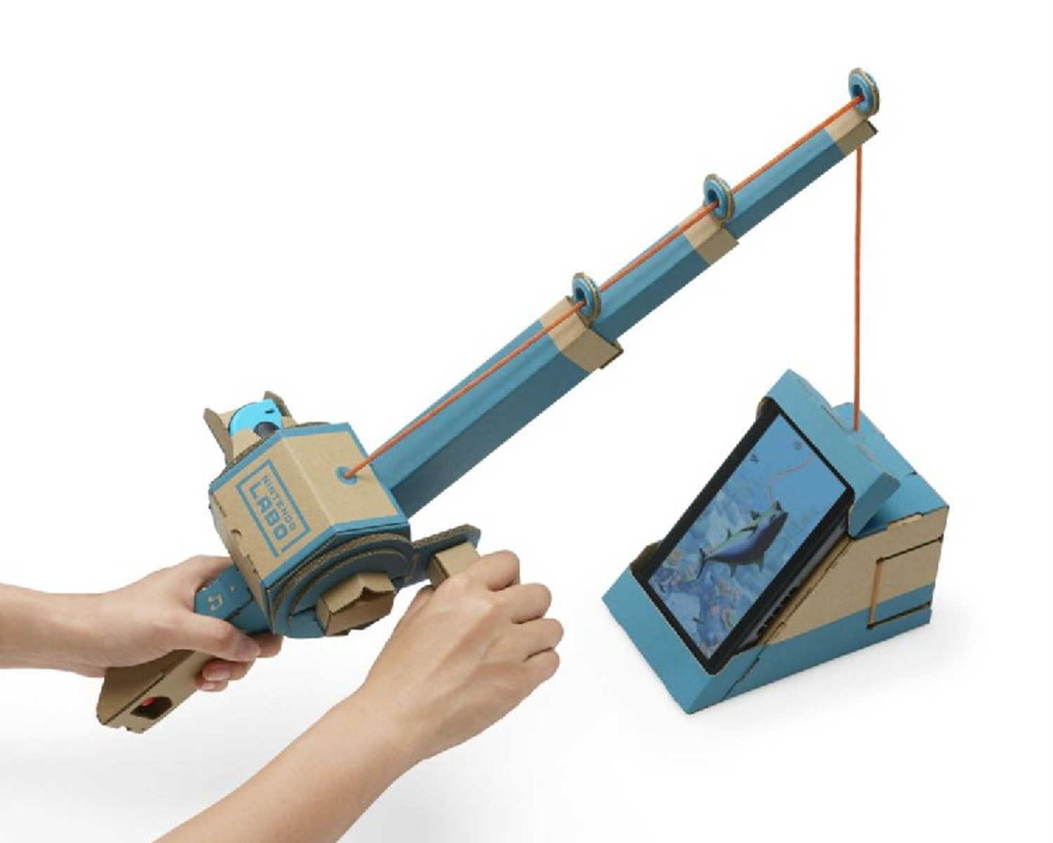 Person verwendet eine Nintendo Labo Angelrute mit Tablet, das ein Angelspiel anzeigt. Pappe-Konstruktion.