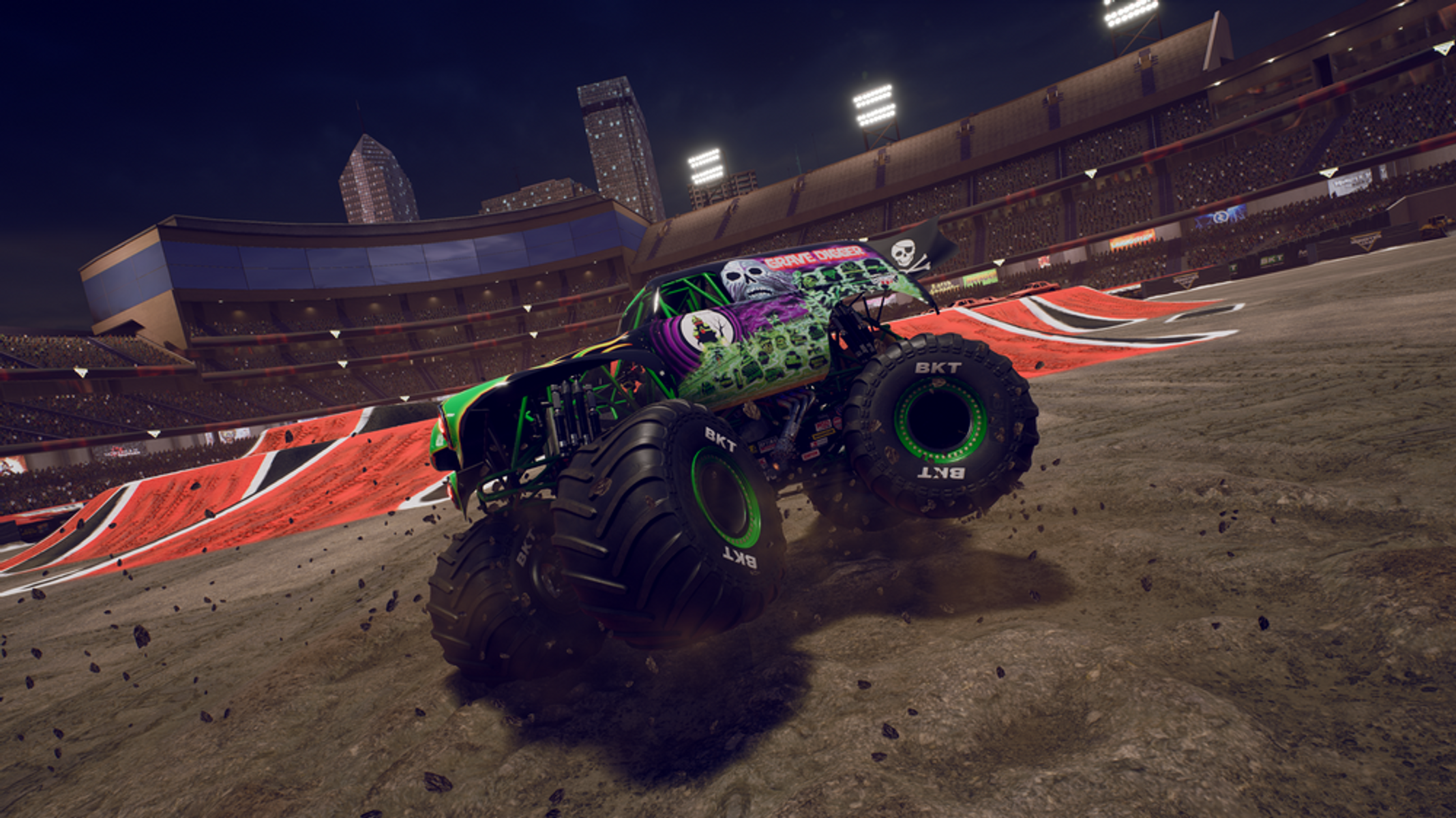 Monster truck, zielony i czarny, na stadionie. Ciężarówka jest w powietrzu, zaraz wyląduje.