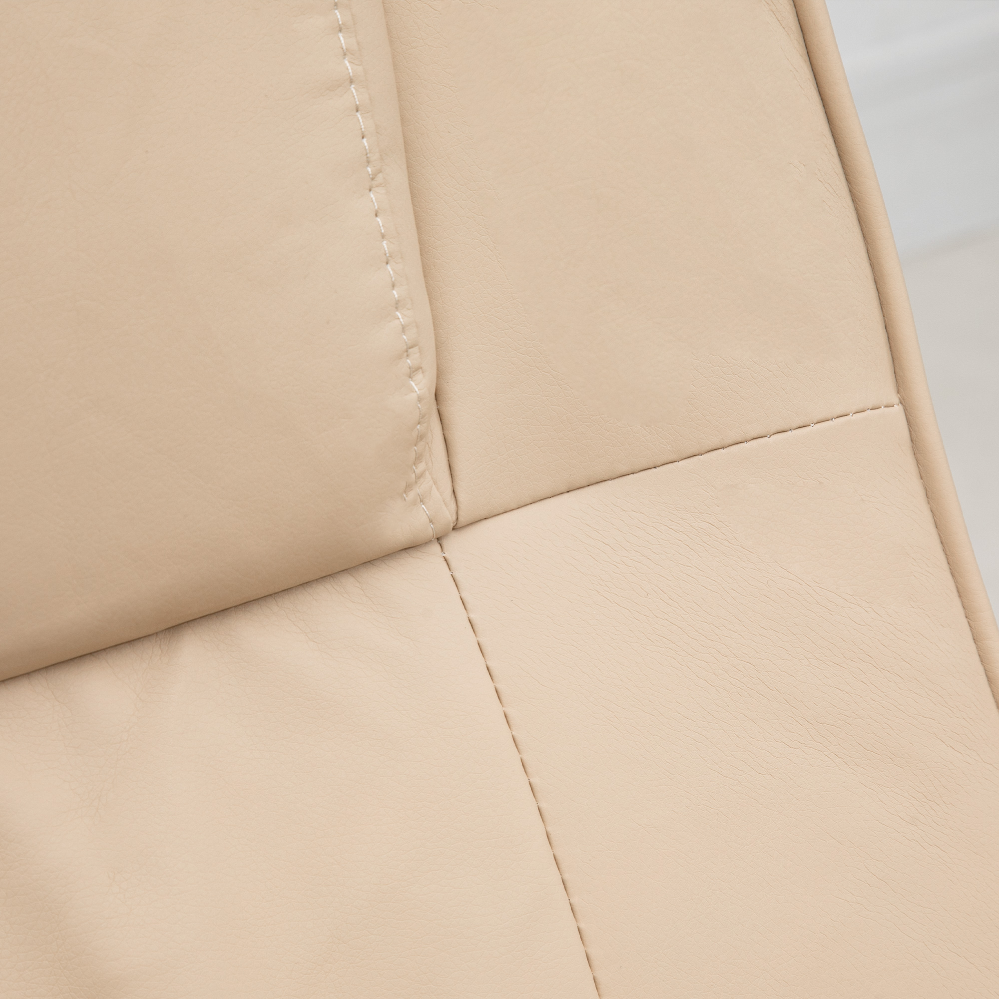 Primer plano de material de cuero beige con costuras visibles. El cuero tiene una superficie texturizada y está bien iluminado.