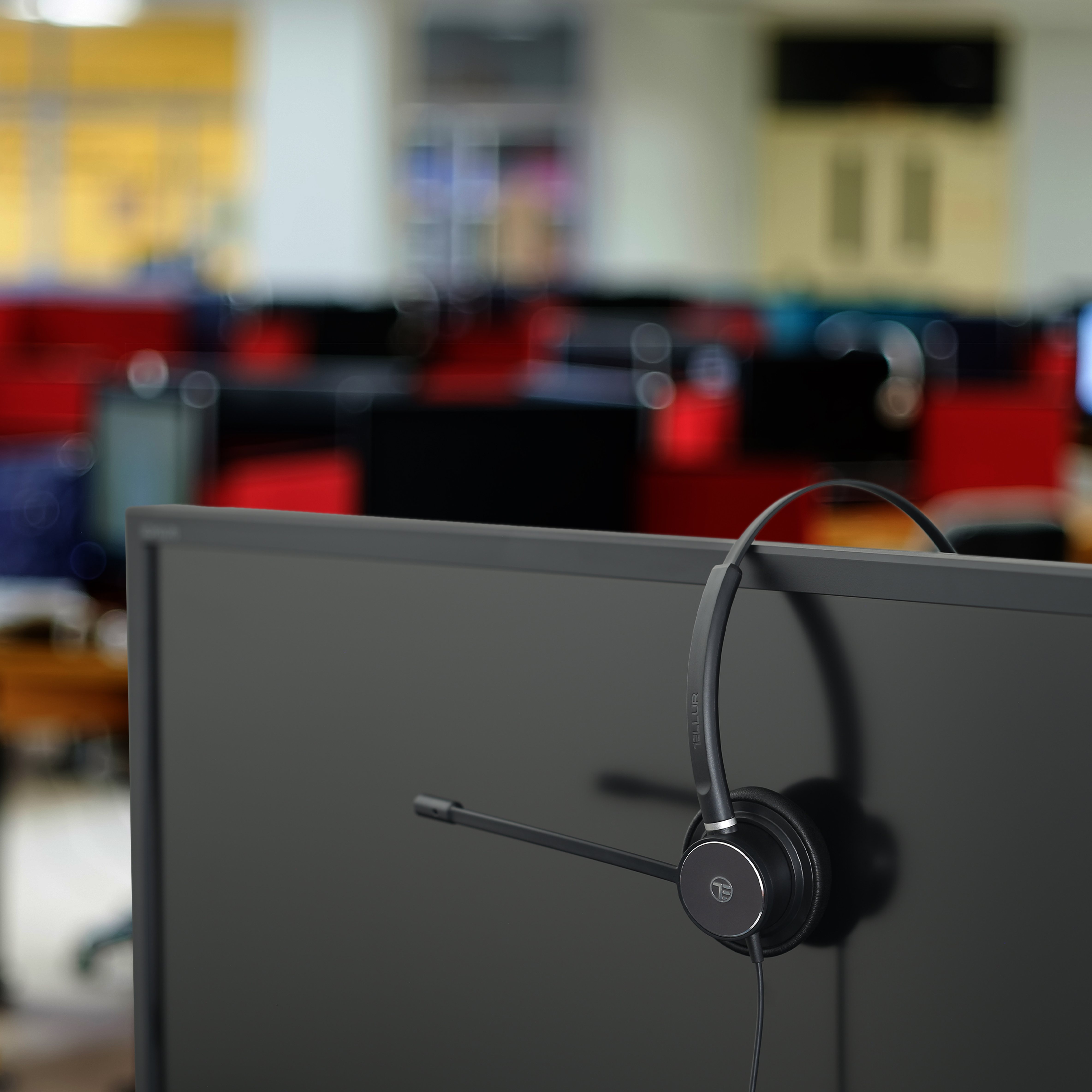 Czarny zestaw słuchawkowy na monitorze komputera w biurze. Tło jest rozmyte.