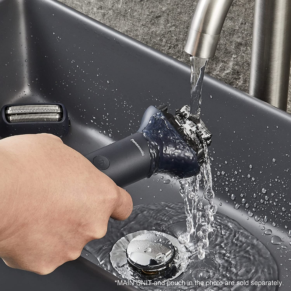 Ręka osoby opłukuje czarną golarkę pod bieżącą wodą w ciemnym zlewie. Widoczna osobna głowica.