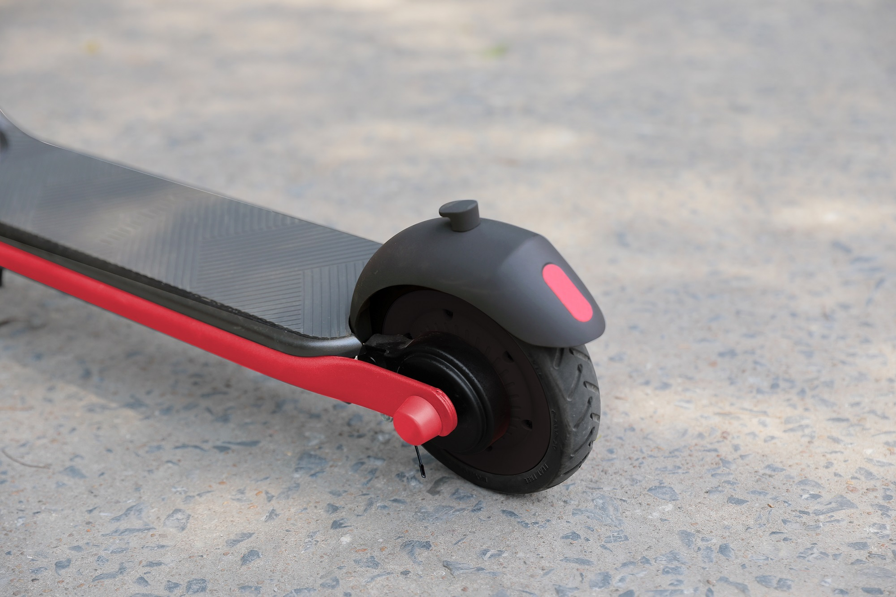 Vista posteriore di uno scooter elettrico rosso e nero su una superficie grigia.