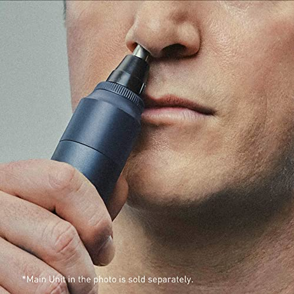 Un homme se coupant les poils du nez avec un petit outil de toilettage bleu foncé.