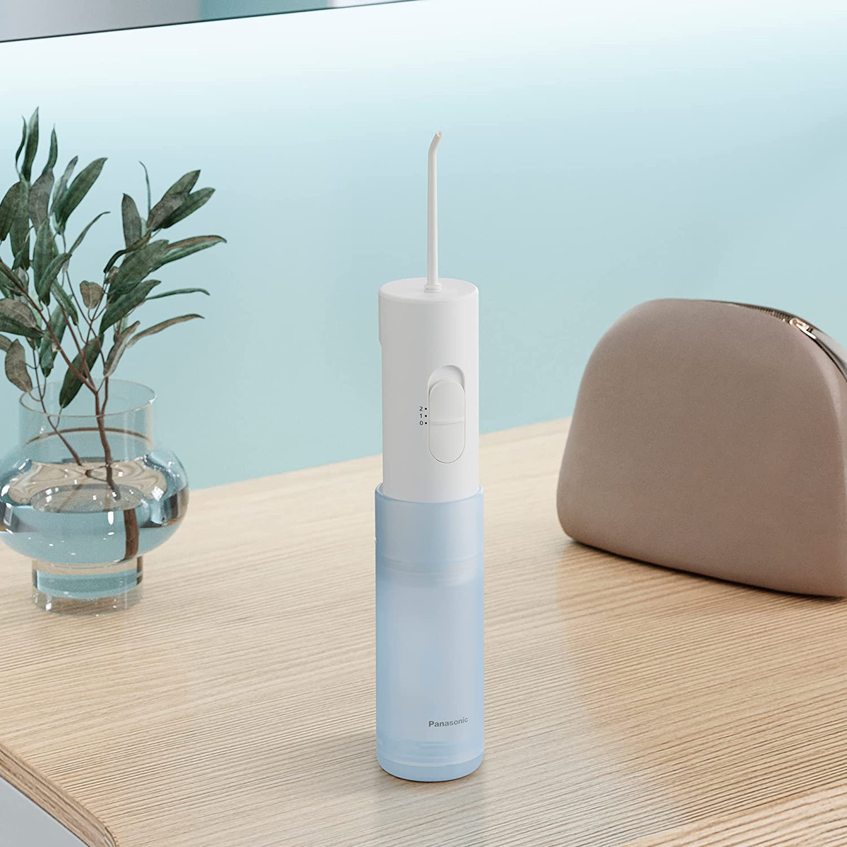 Biało-niebieski irygator z pojemnikiem na drewnianej powierzchni, z wazonem i torebką.