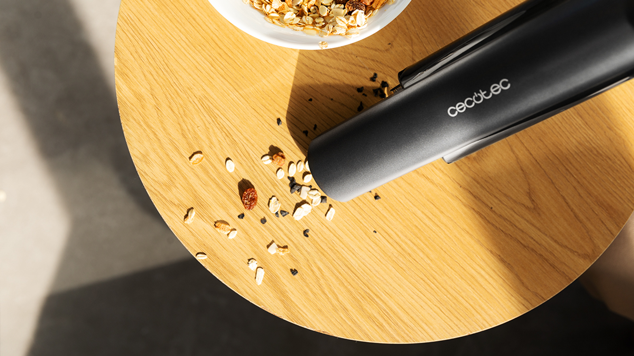 Boquilla de aspiradora sobre mesa de madera, migas de comida dispersas.