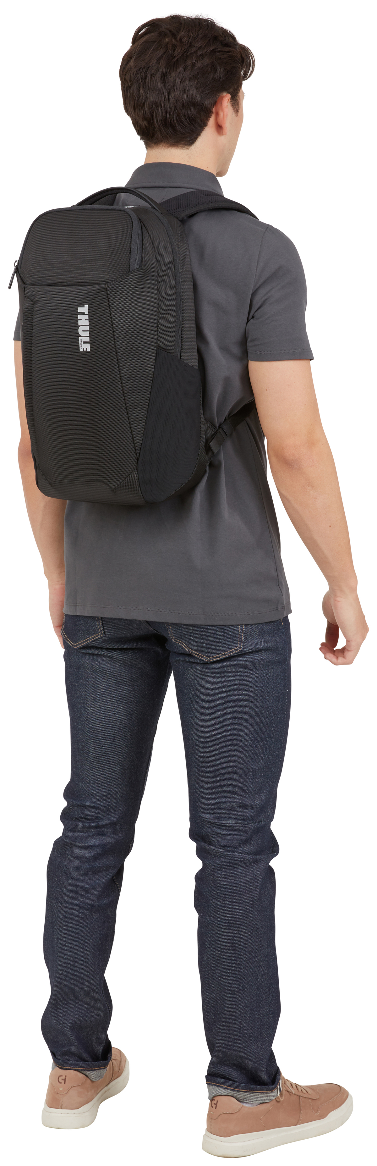 Eine Person von hinten, in Jeans und grauem T-Shirt, mit einem schwarzen Rucksack mit Thule-Logo.