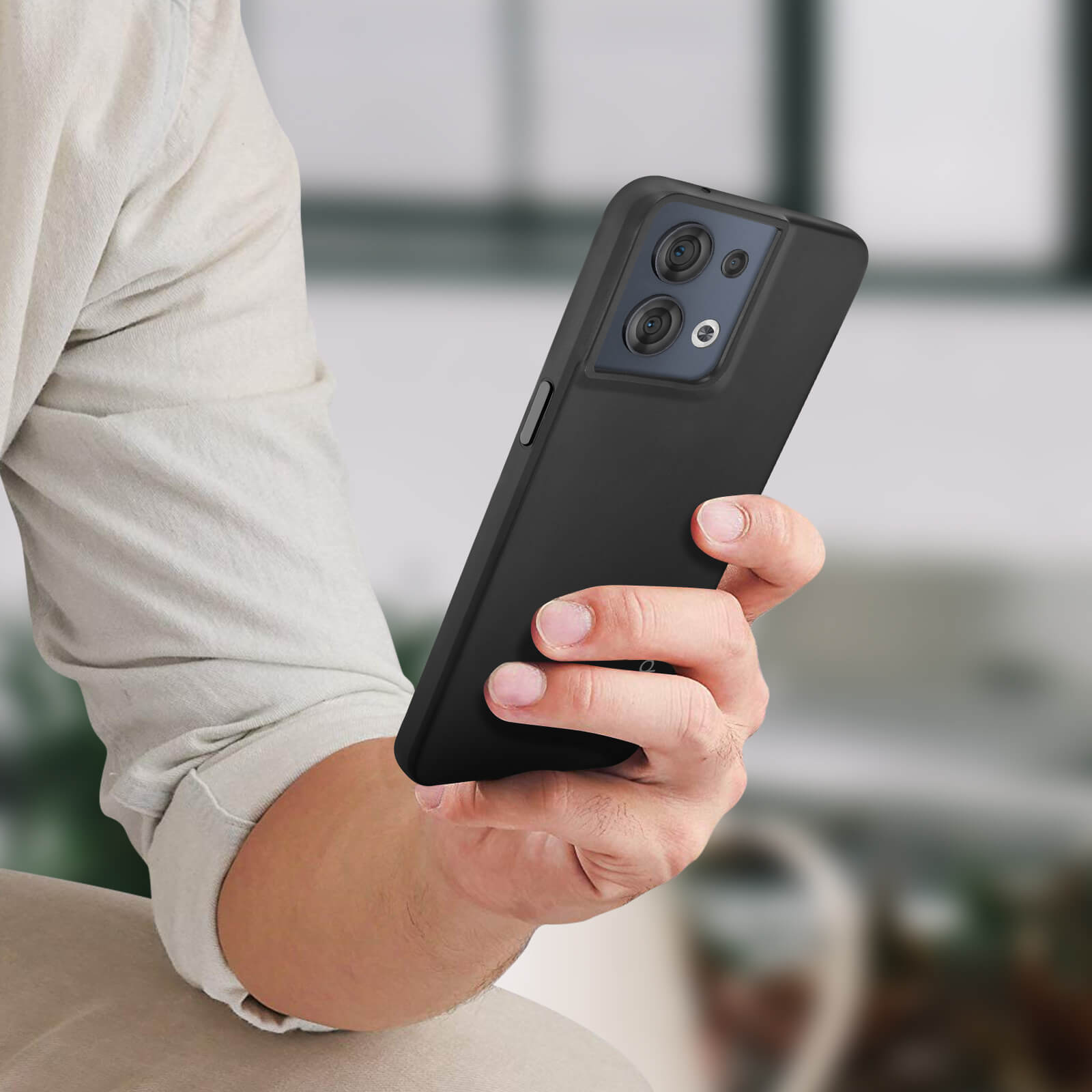 Une personne tenant un téléphone dans un étui noir. Le téléphone a une configuration à double caméra.