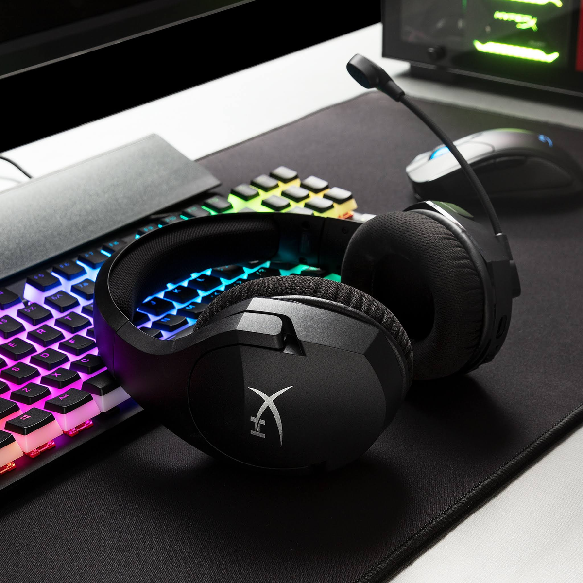 Czarne słuchawki dla graczy z mikrofonem na macie, klawiatura i mysz w tle.