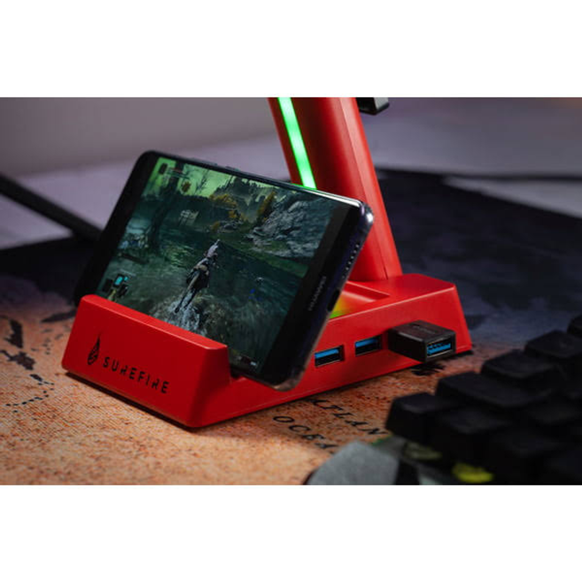 Un soporte de teléfono rojo que sostiene un teléfono que muestra un juego. Los puertos USB son visibles.