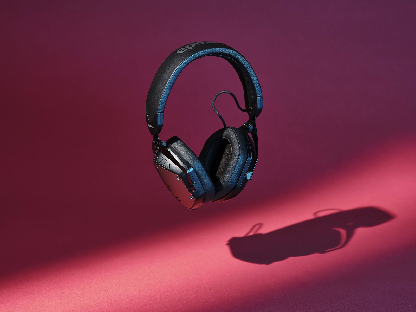 Casque en l'air sur fond rouge. Le casque est noir et rouge, avec une ombre en dessous.