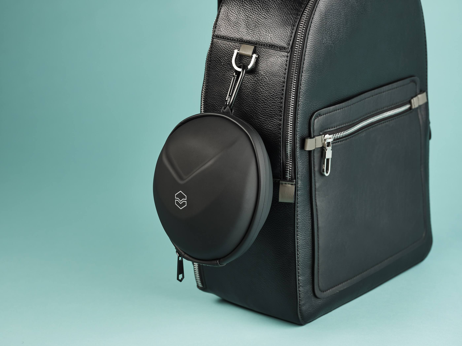 Étui de transport noir fixé à un sac à dos noir, sur fond bleu-vert.