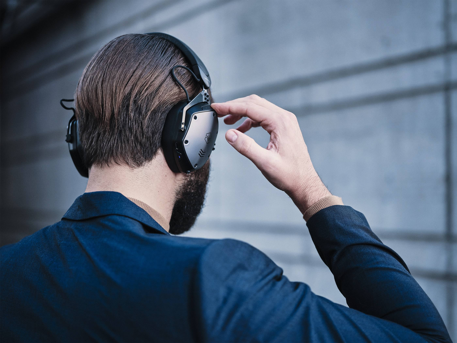 Homme portant un casque noir, regardant un mur, avec sa main sur le casque.