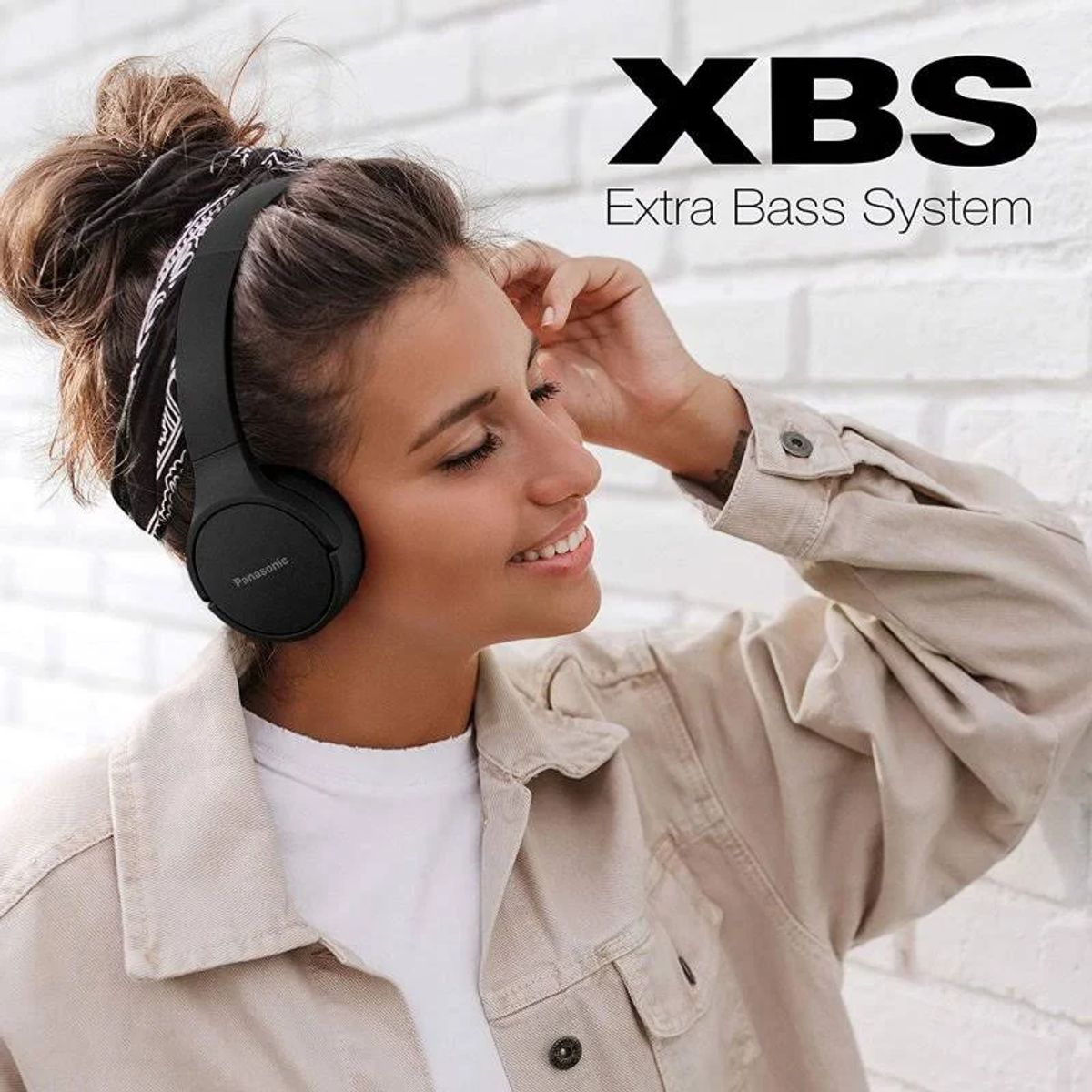 Junge Frau mit Stirnband trägt schwarze Kopfhörer. Der Text 'XBS Extra Bass System' ist sichtbar.
