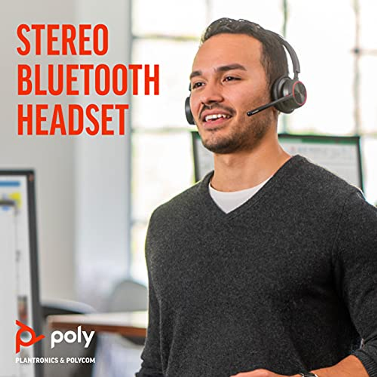 Mężczyzna w zestawie słuchawkowym, uśmiechnięty, w otoczeniu biurowym. Logo Poly widoczne.
