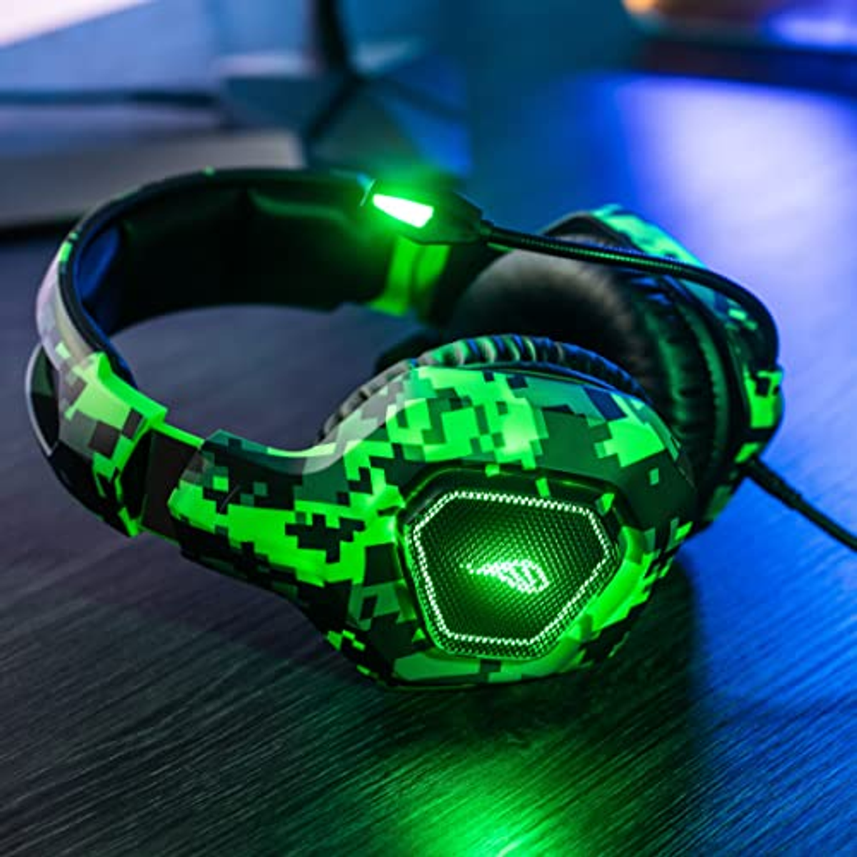 Green pixelated gaming headset on a wooden surface. The headset is lit up. The background is dark.
