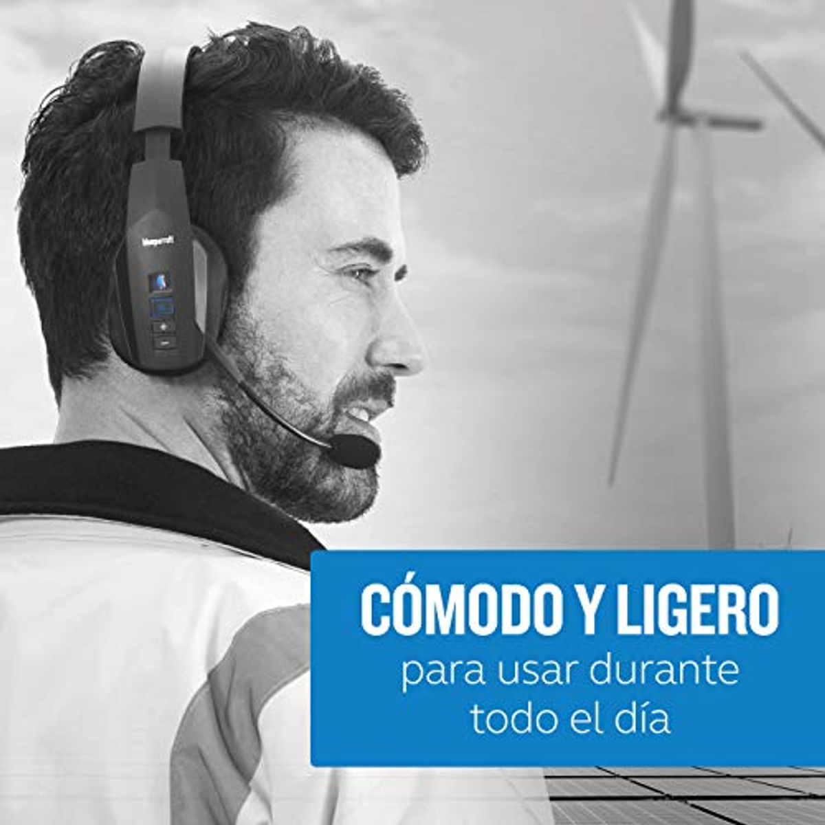 Mężczyzna w czarnych słuchawkach z mikrofonem. Scena plenerowa z turbinami wiatrowymi w tle.