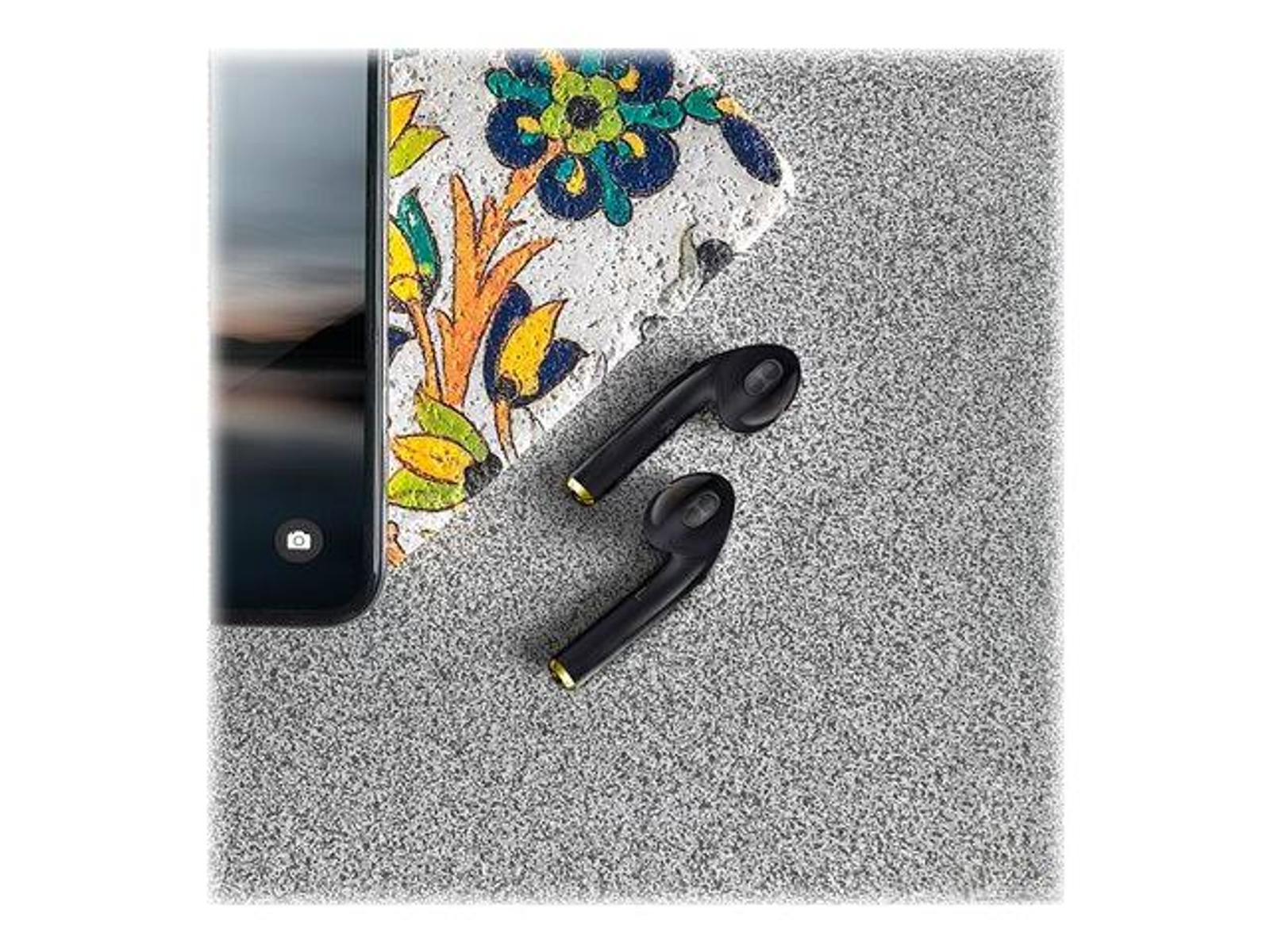 Auricolari wireless neri e telefono su superficie grigia con pietra.
