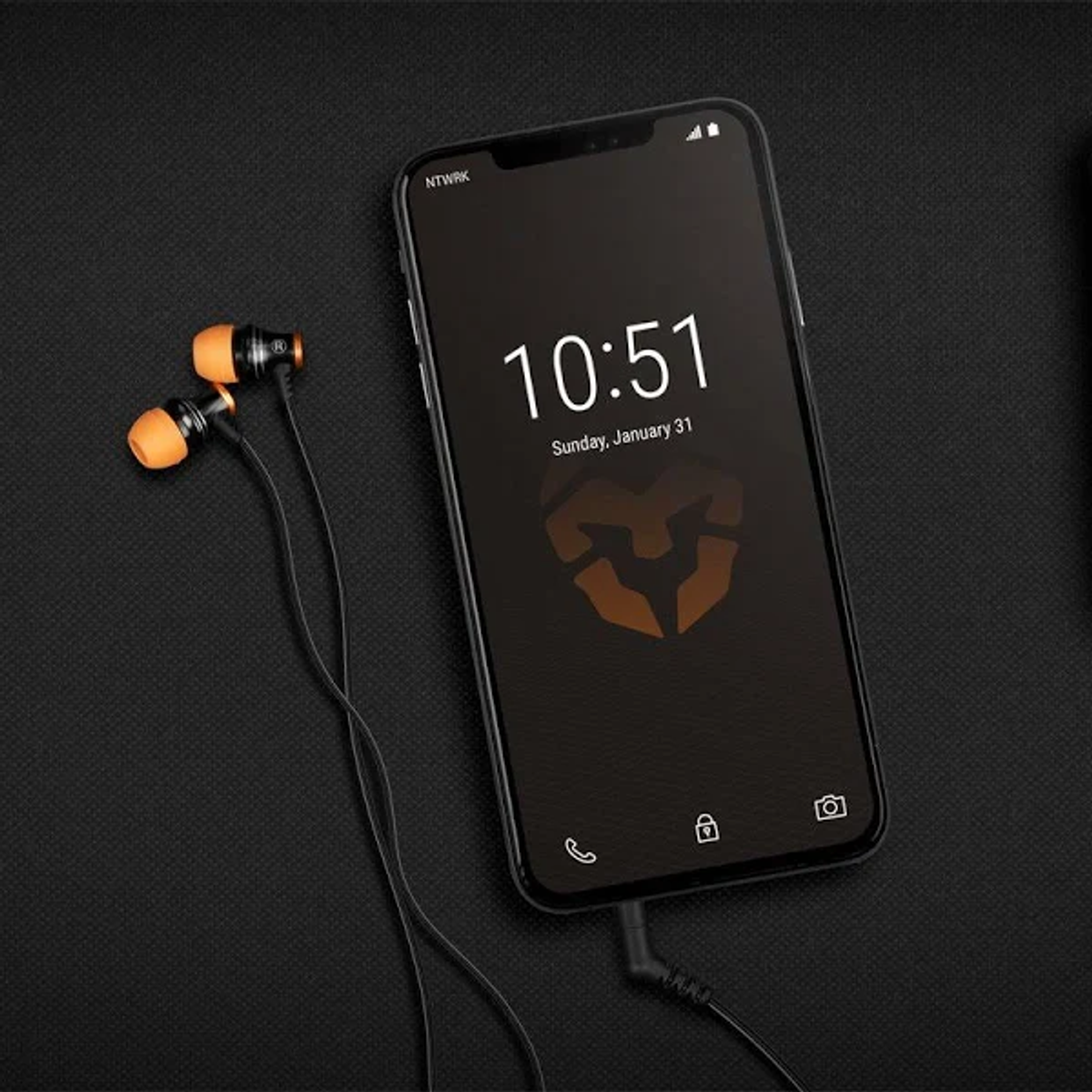 Schwarzes Smartphone mit orangefarbenen Ohrhörern, schwarzer Hintergrund.