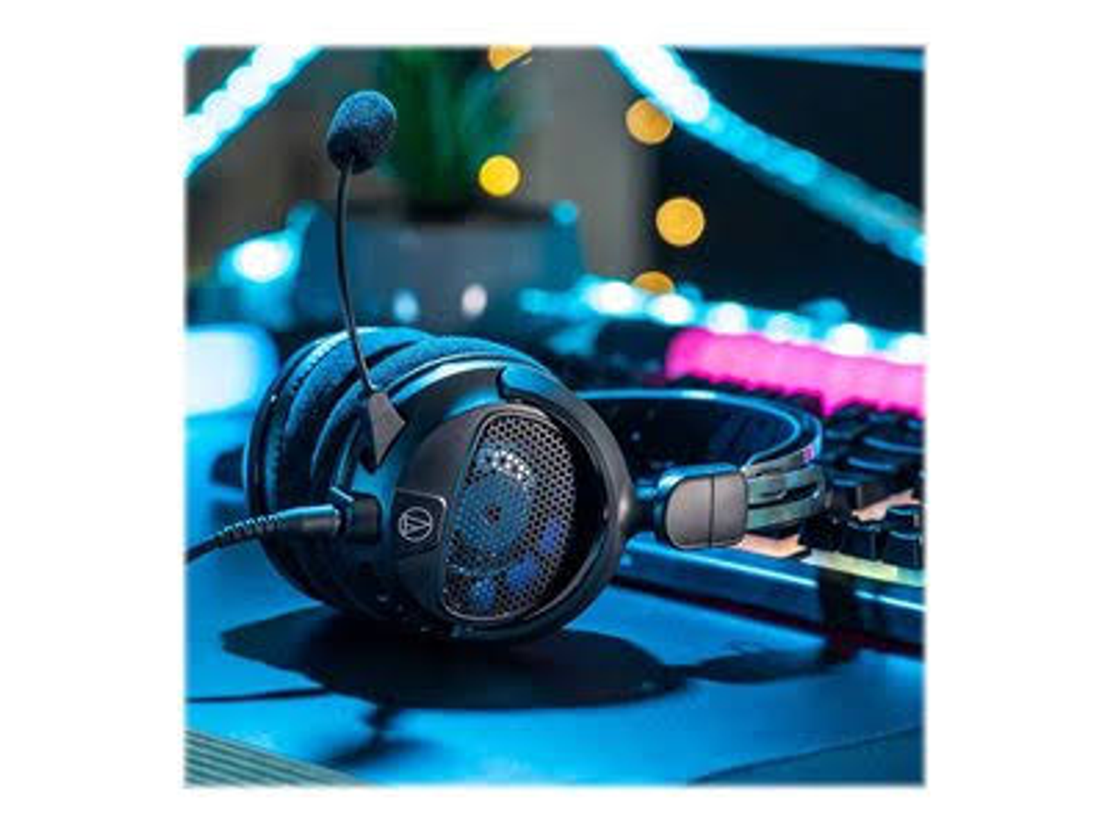 Zestaw słuchawkowy do gier z mikrofonem na biurku. Klawiatura i światła w tle.