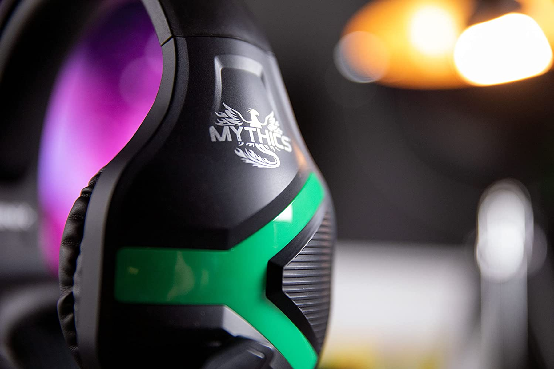 Zbliżenie czarno-zielonego zestawu słuchawkowego dla graczy, widoczny logo Mythics. Rozmyte tło.