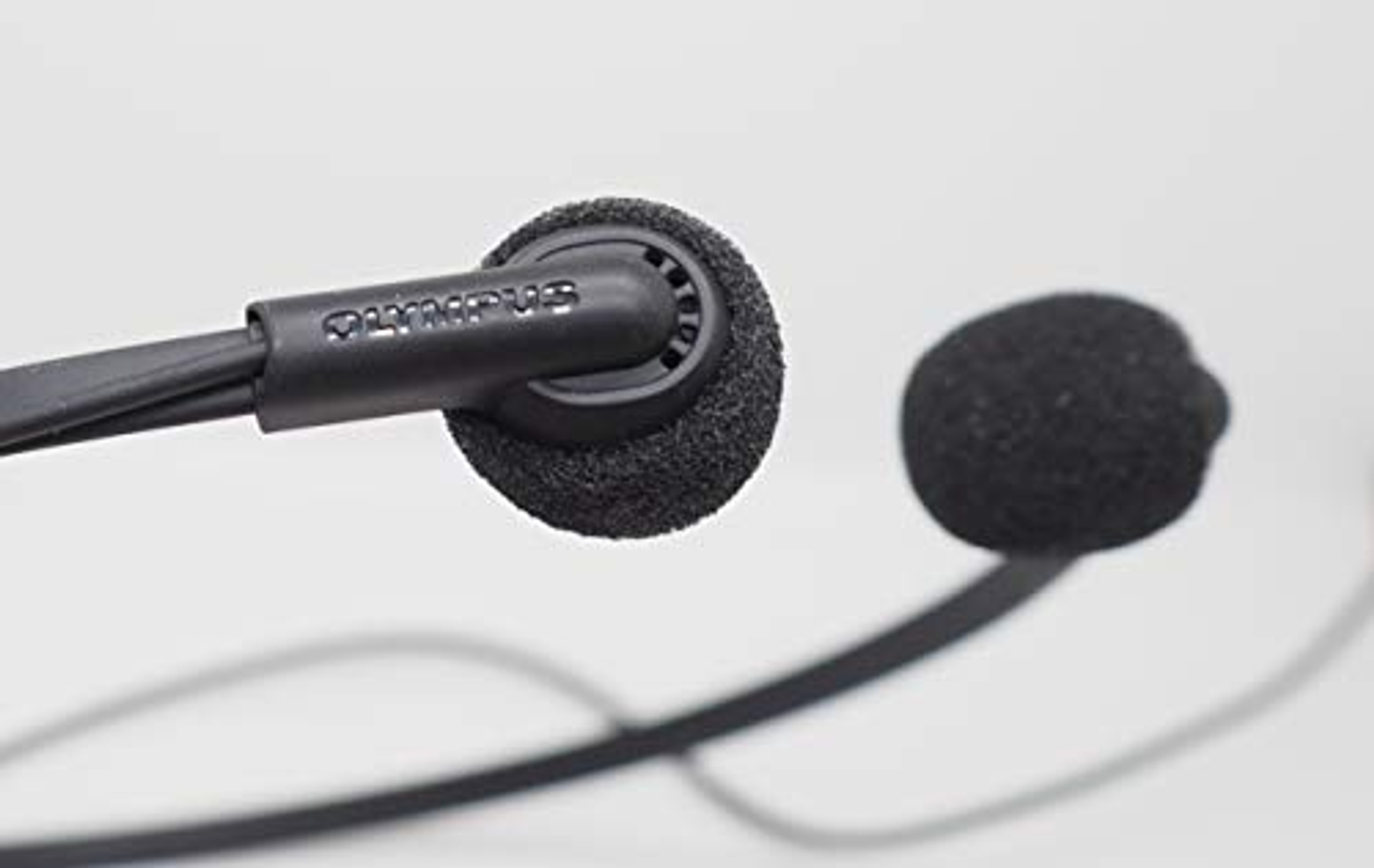 Primo piano di auricolari Olympus neri. Gli auricolari e il microfono sono neri.