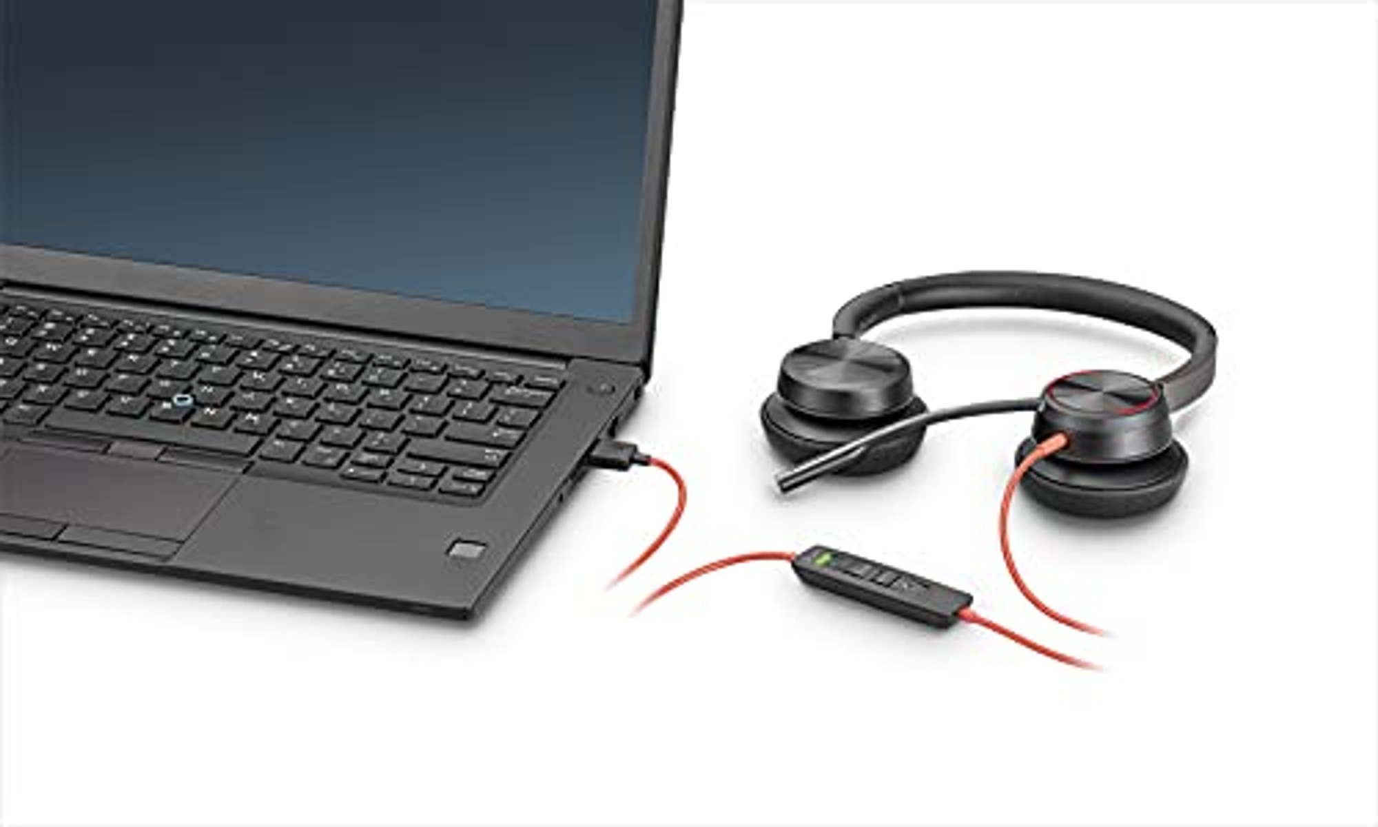 Auriculares negros conectados a un portátil. Un cable rojo está conectado. Los auriculares tienen un panel de control.