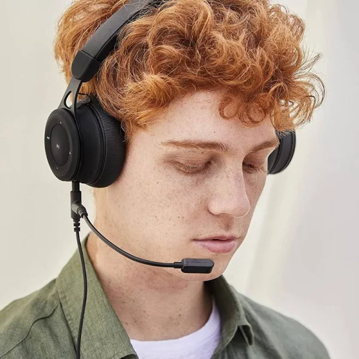 Hombre con cabello rizado rojo usando auriculares negros con micrófono.