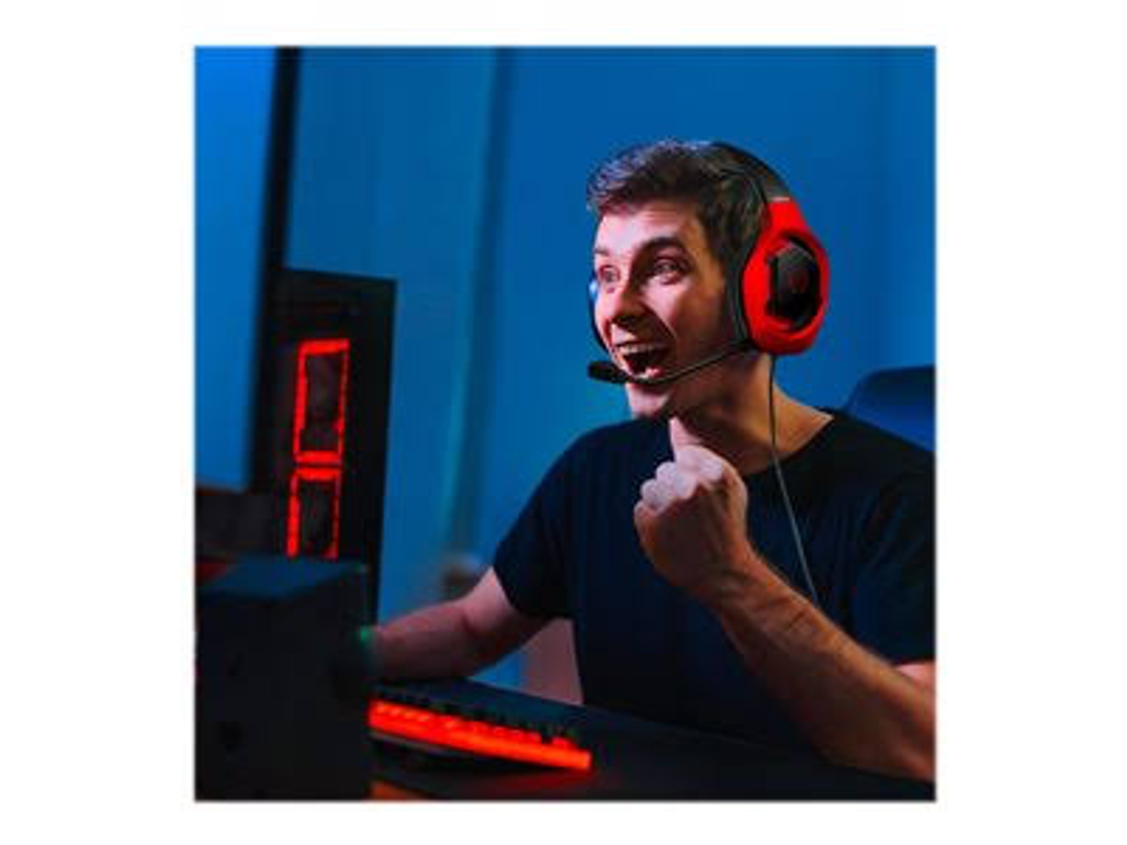 Mężczyzna w zestawie słuchawkowym z czerwonymi akcentami. Jest podekscytowany, patrząc na ekran.