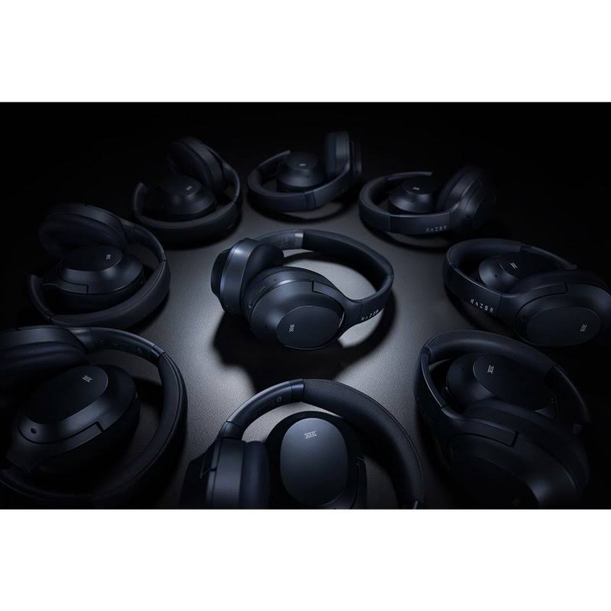 Słuchawki ułożone w okrąg, głównie czarne, na ciemnej powierzchni z miękkim oświetleniem.