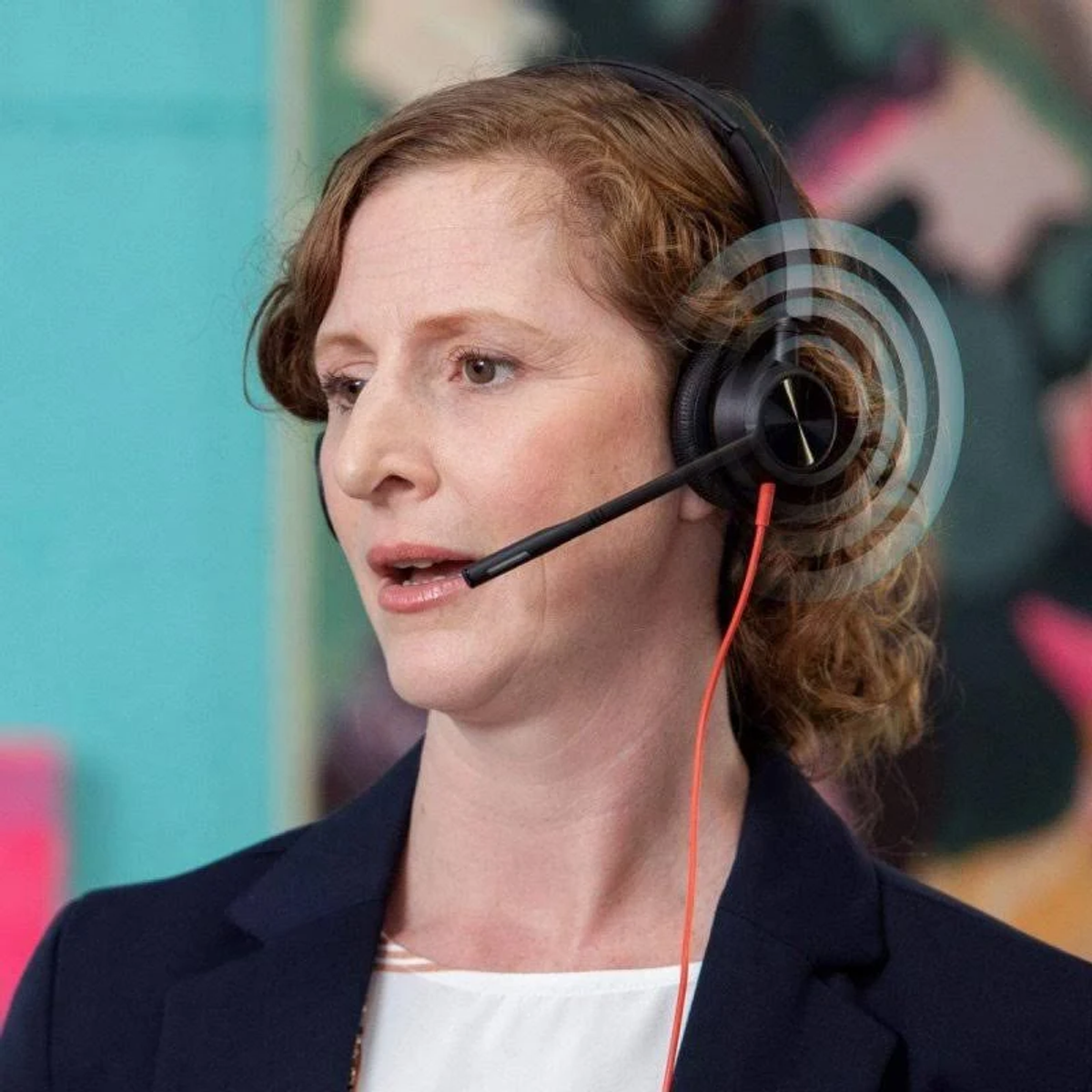 Kobieta w zestawie słuchawkowym, mówiąca. Grafika w postaci fal dźwiękowych wokół jej głowy. Turkusowe i różowe tło.