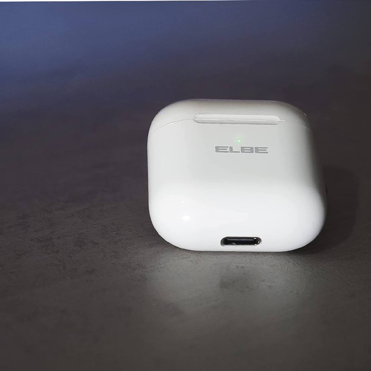 Białe etui ładujące do słuchawek. Etui ma logo ELBE i port ładowania. Widoczne zielone światło.