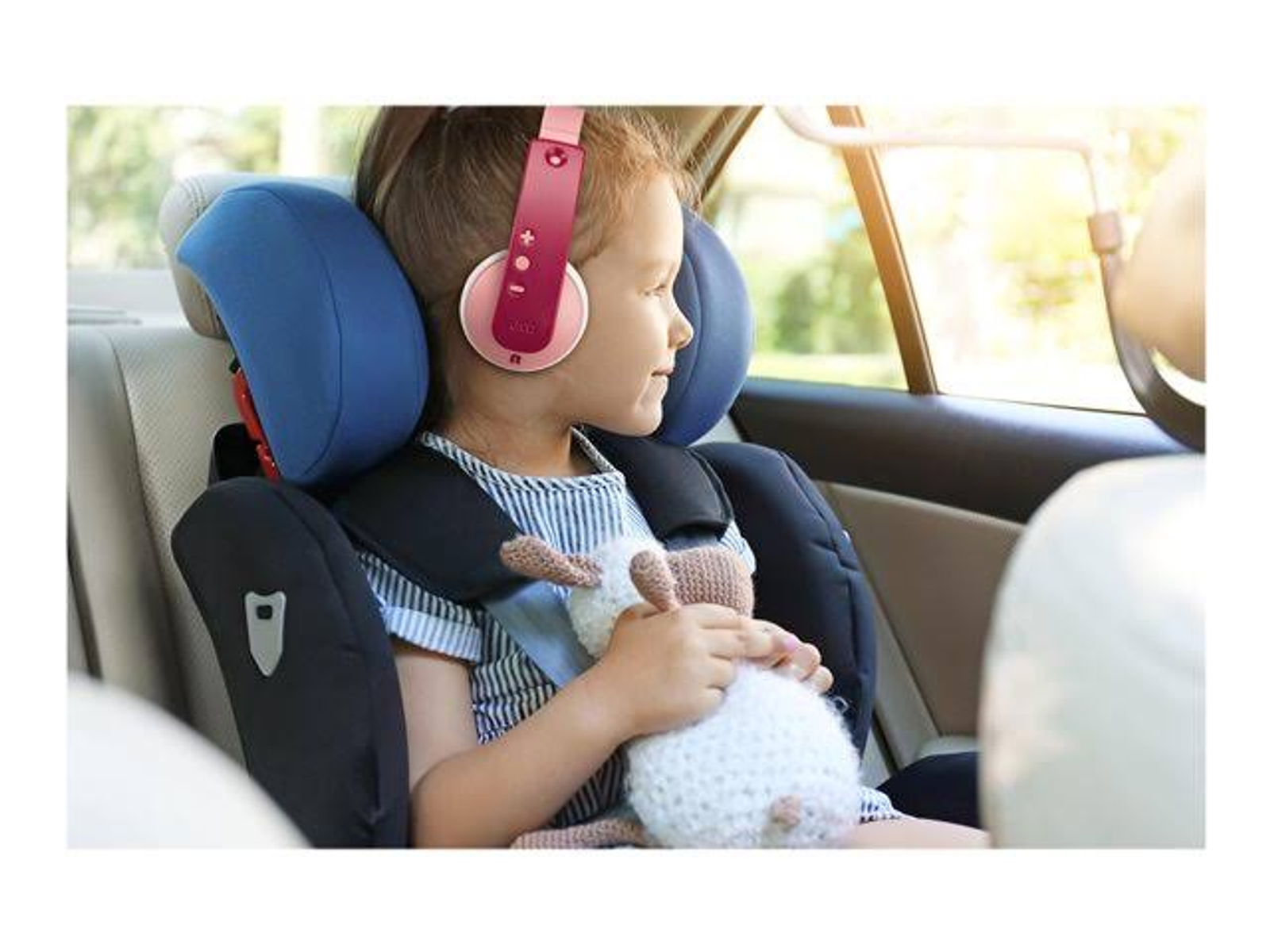 Un bambino in seggiolino con cuffie rosa, che tiene un peluche.