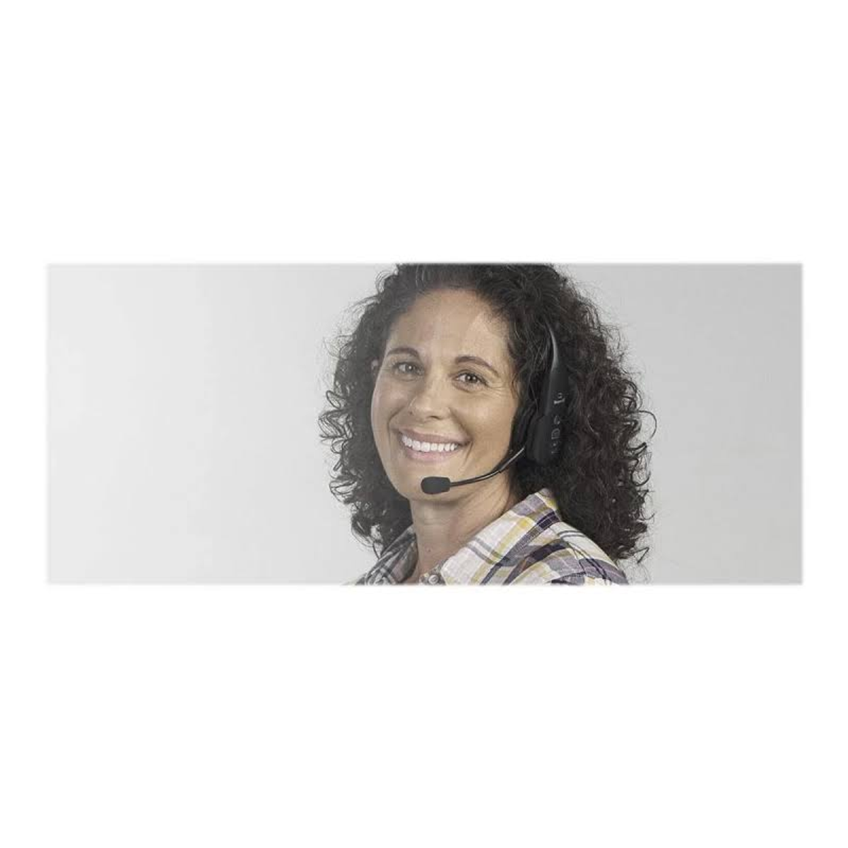 Kobieta w zestawie słuchawkowym uśmiecha się, zdjęcie z górnej części ciała.