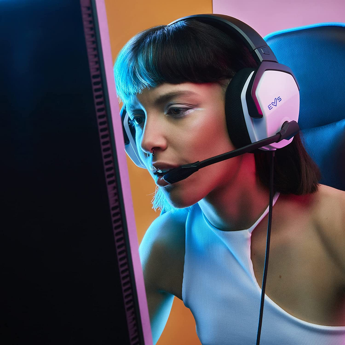 Kobieta w zestawie słuchawkowym z mikrofonem, grająca przed monitorem.