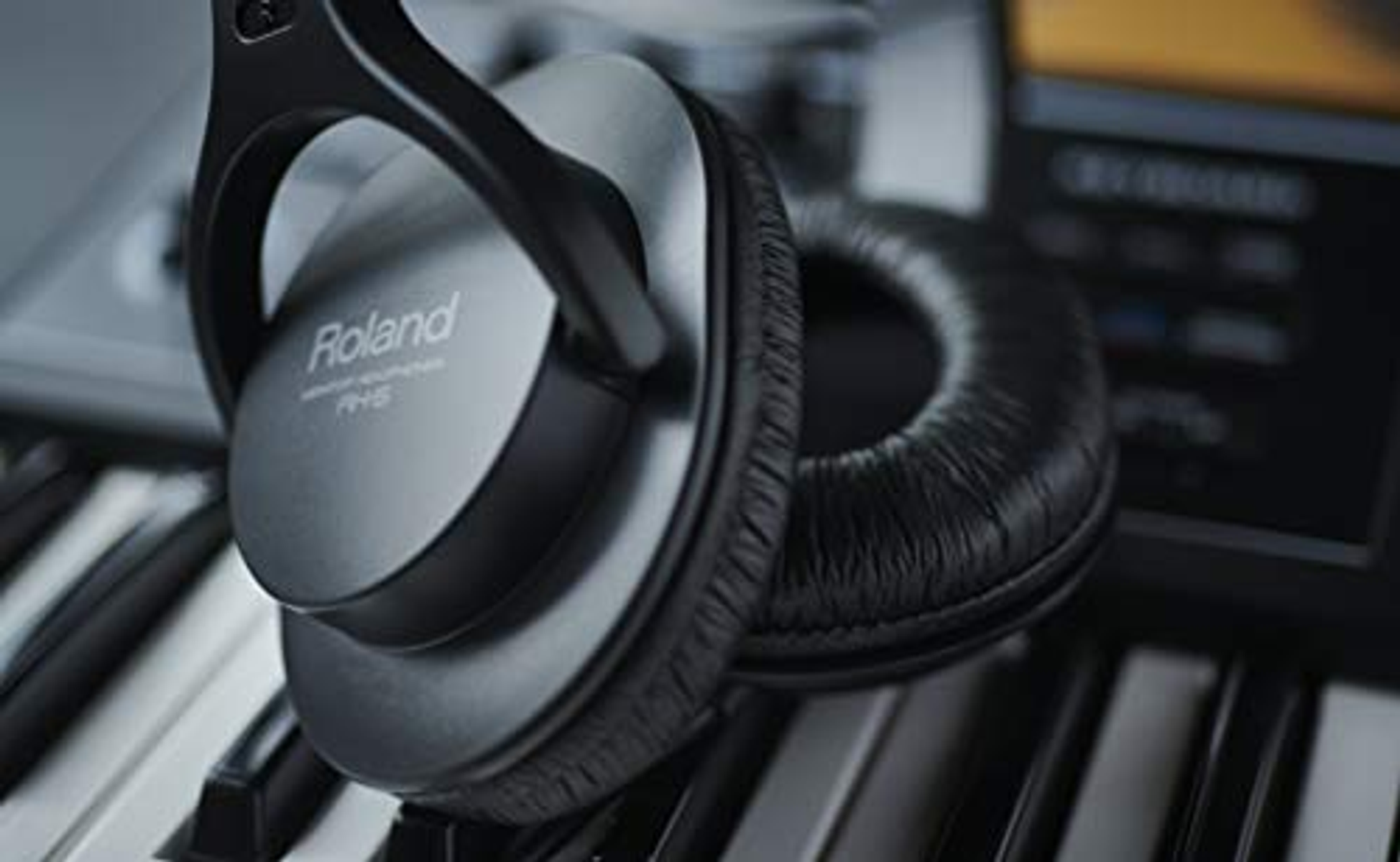 Casque argenté sur un clavier de piano. La marque 'Roland' est visible.