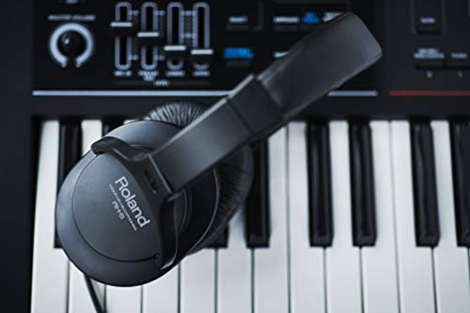 Casque noir posé sur un clavier. Marque Roland visible. Touches noires et blanches.