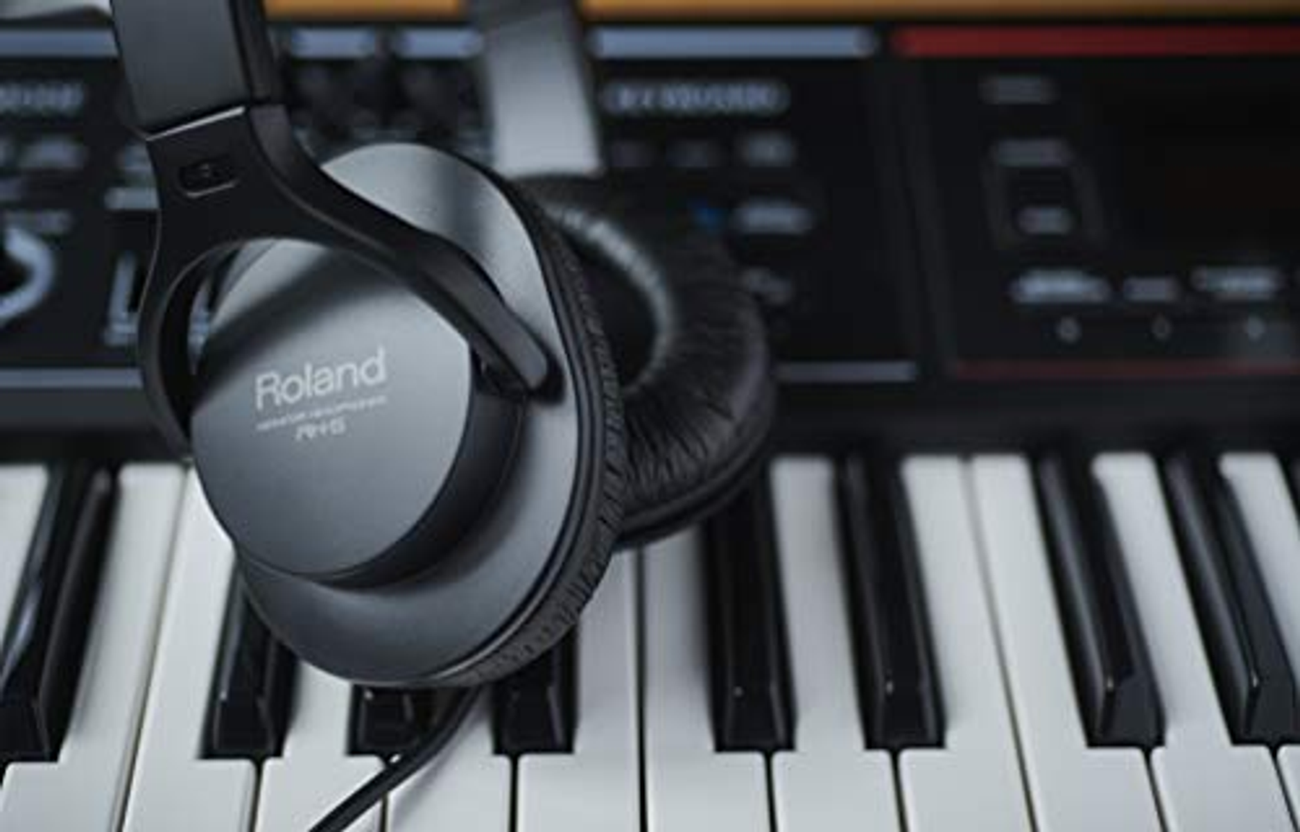 Casque noir sur un clavier de piano, avec un clavier flou en arrière-plan.