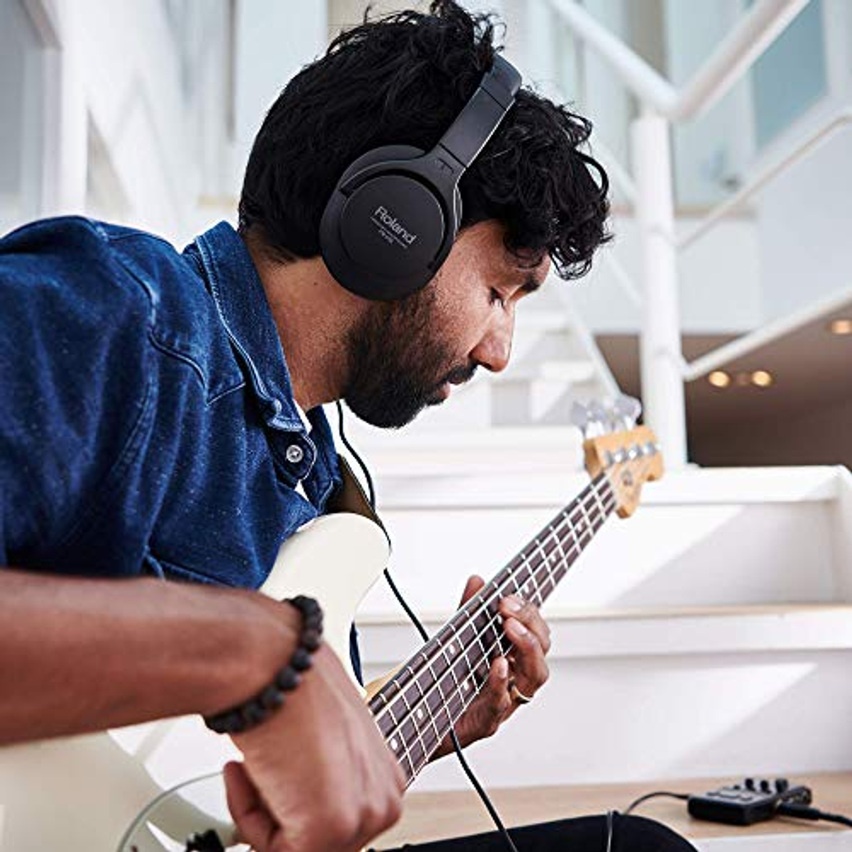 Homme jouant d'une guitare blanche, portant un casque noir.