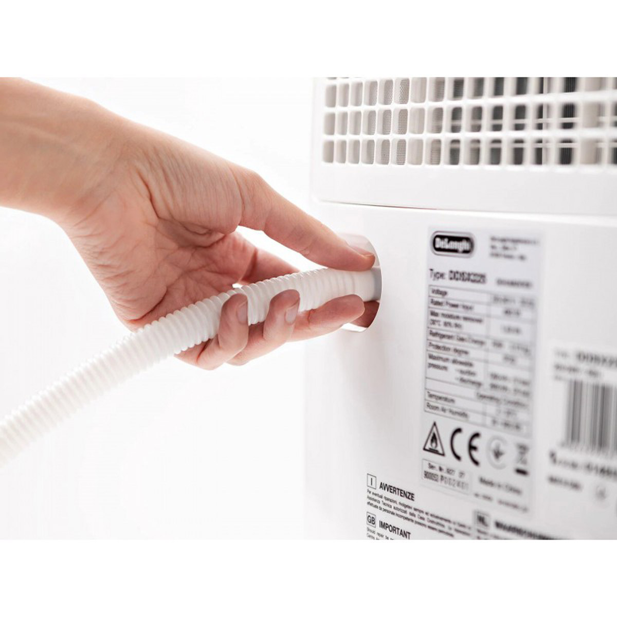 Ręka wkładająca biały wąż do białego klimatyzatora. Białe tło.