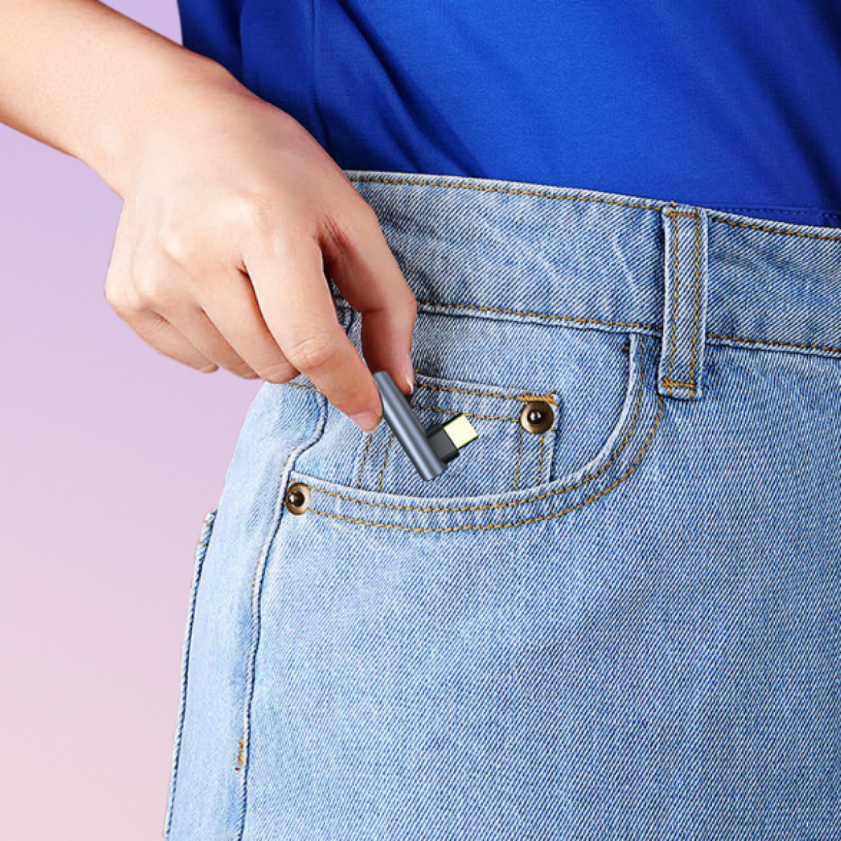 Osoba trzyma mały adapter w kieszeni dżinsów. Kieszeń jest niebieska.