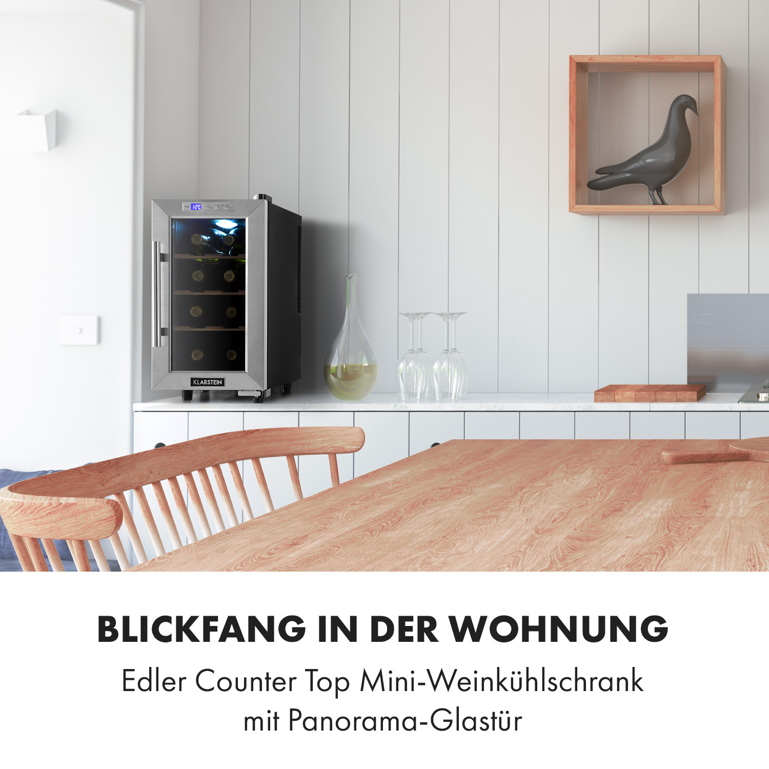 Weinkühler auf einem weißen Schrank. Ein Holztisch und Stuhl im Vordergrund. Text: Blickfang in der Wohnung.