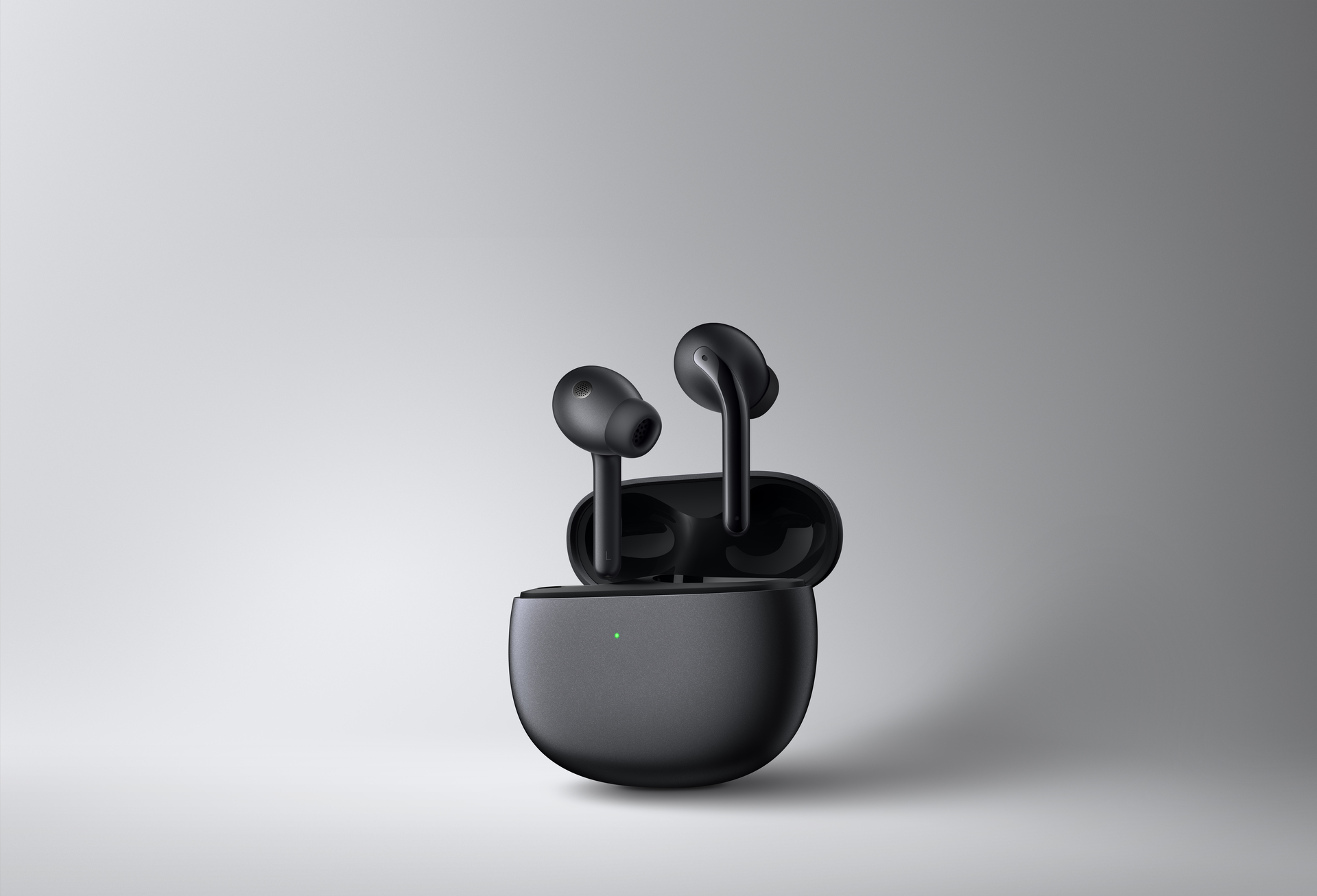 Auriculares inalámbricos negros en un estuche de carga negro, con una luz verde en el estuche.