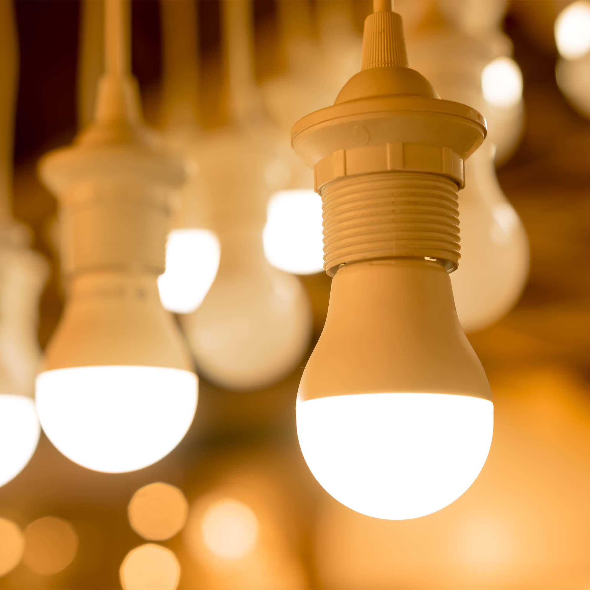 Kilka świecących żarówek LED wiszących pod sufitem, ciepłe światło.