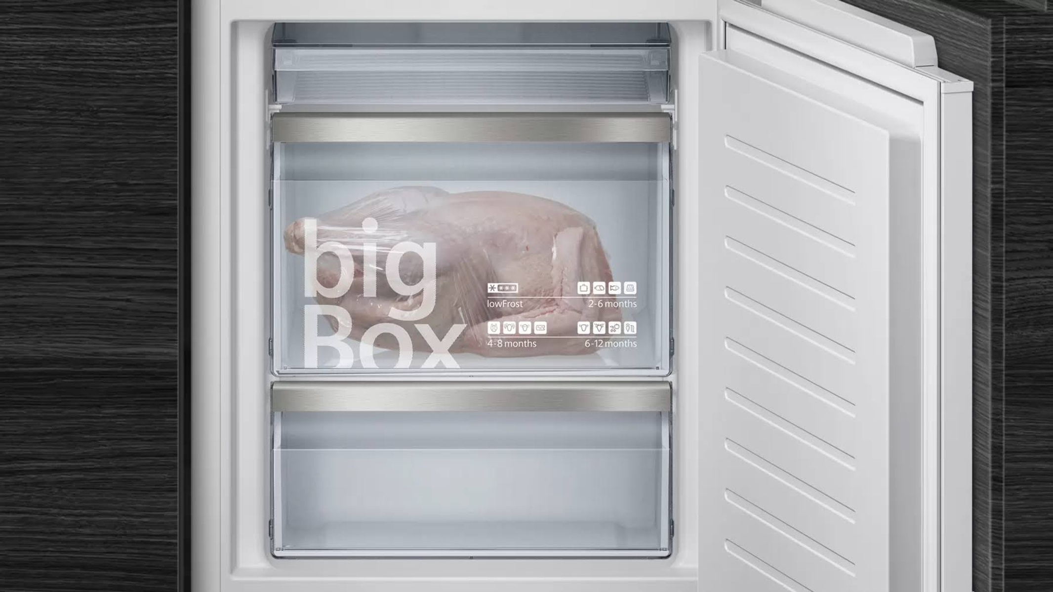 Frigorifero aperto con tacchino crudo nel cassetto 'bigBox', sfondo in legno scuro.