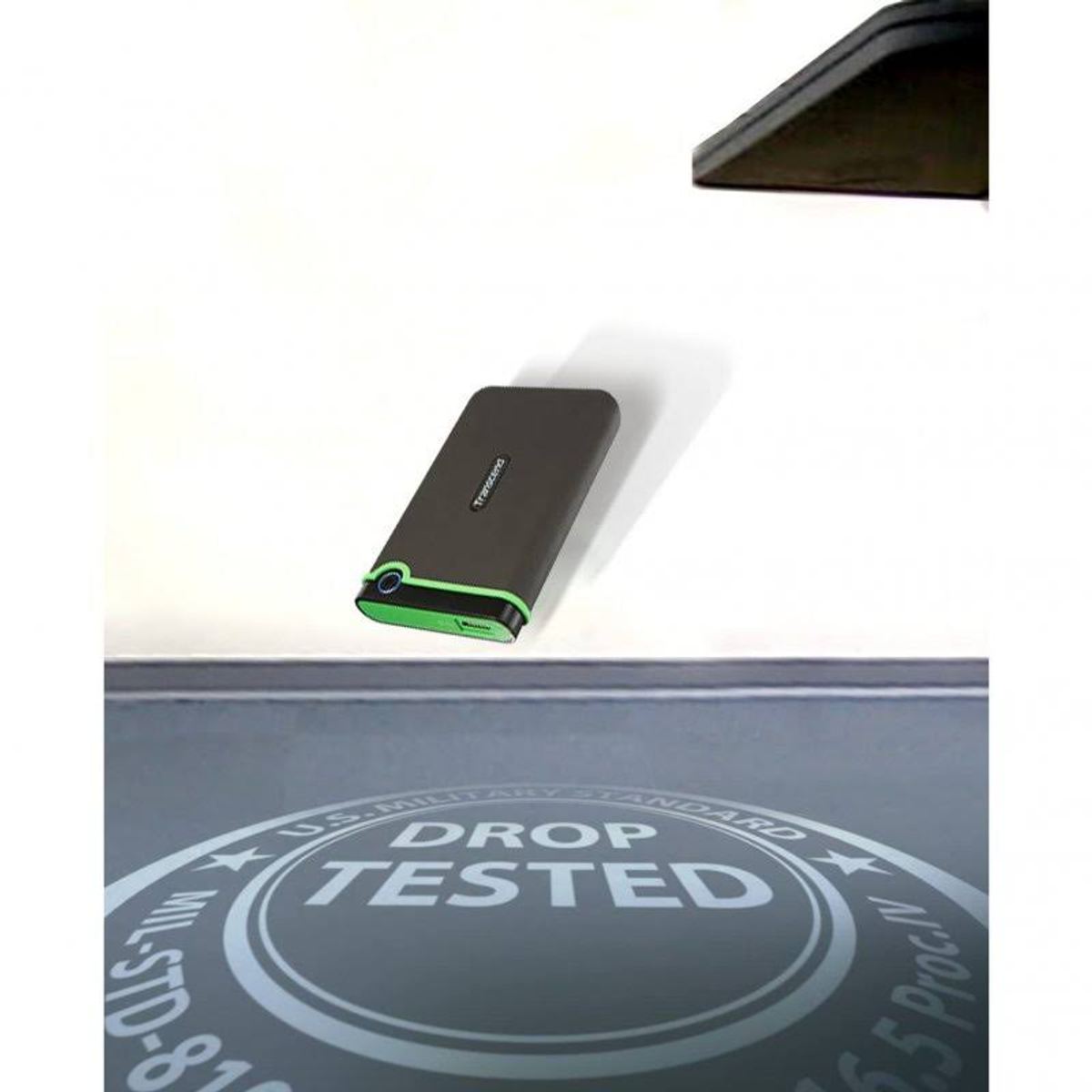 Dysk twardy leży na białej powierzchni z logo testu upadku. Ma zielone akcenty i ciemny kolor.