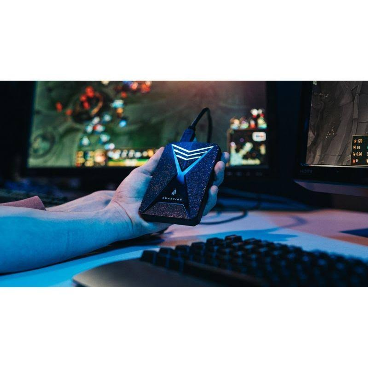 Osoba trzymająca czarny zewnętrzny dysk twardy z niebieskim światłem. Rozmyte tło.