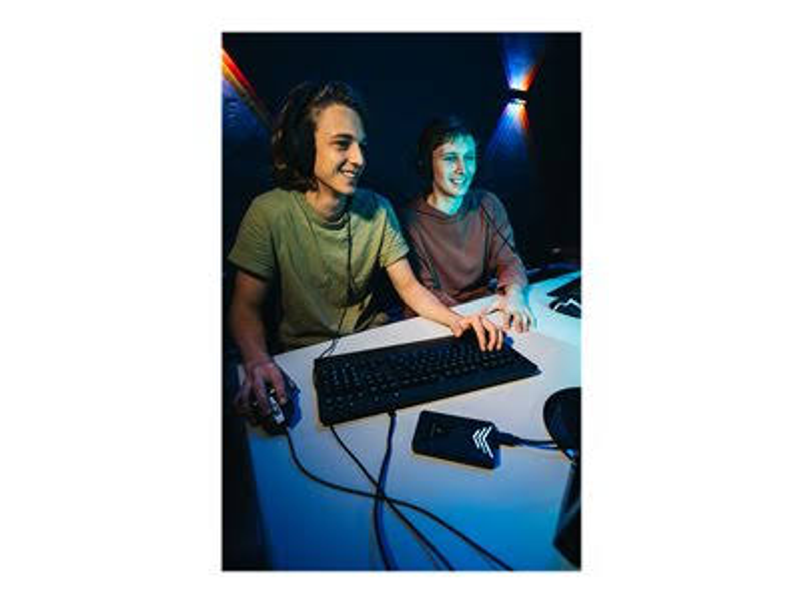 Dwóch graczy w słuchawkach przy biurku, grających za pomocą myszy i klawiatury.