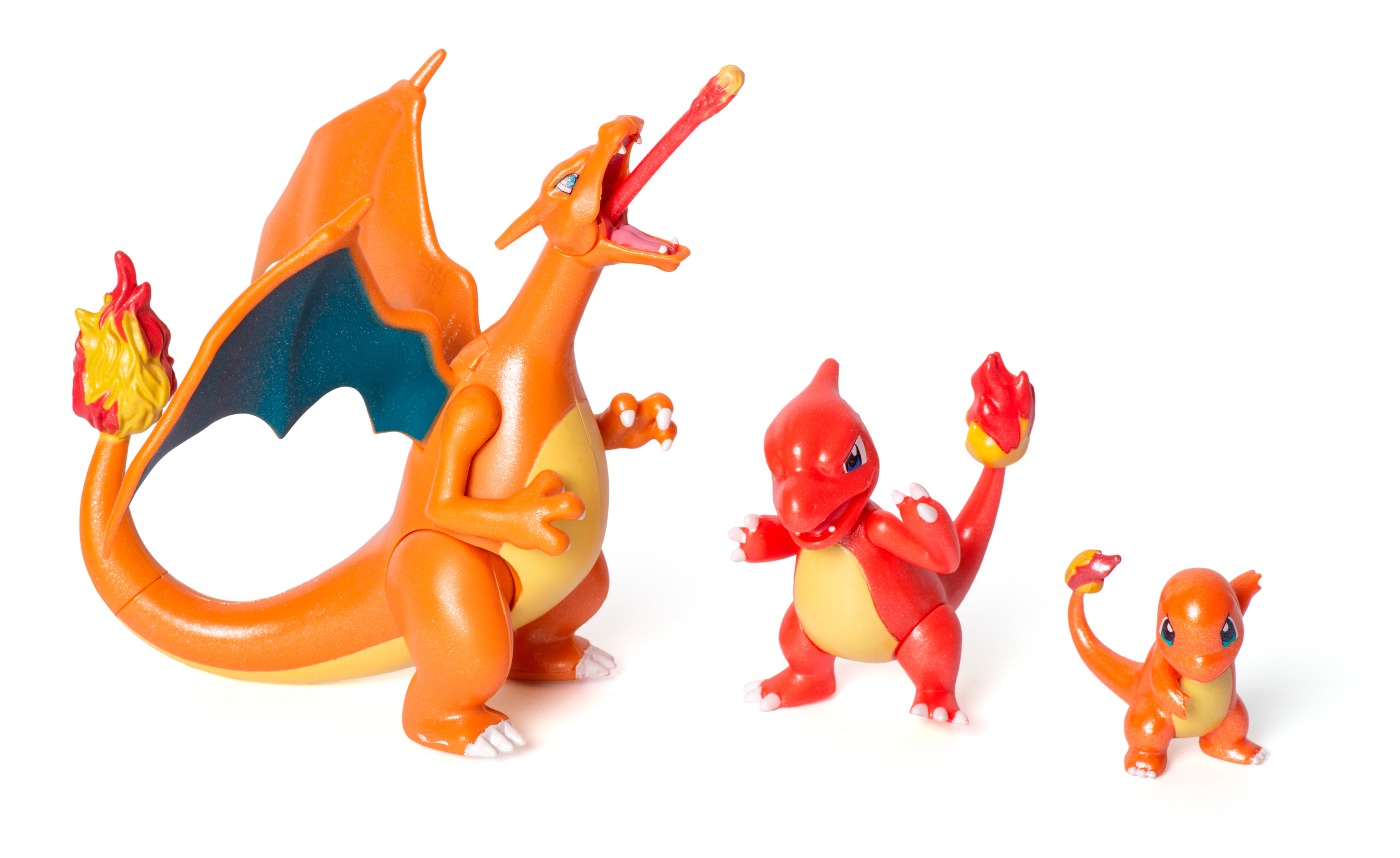 Drei Pokémon-Figuren: Glurak, Glutexo und Glumanda. Glurak ist orange und hat Flügel. Alle auf weißem Hintergrund.